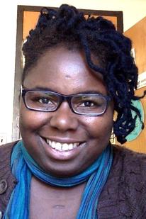 Portrait of smiling black woman wearing glasses and a green scarf.